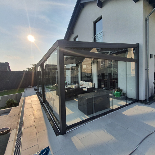 Moderner Sommergarten mit Glas-Schiebetüren und Aluminiumkonstruktion, windgeschützt und lichtdurchflutet